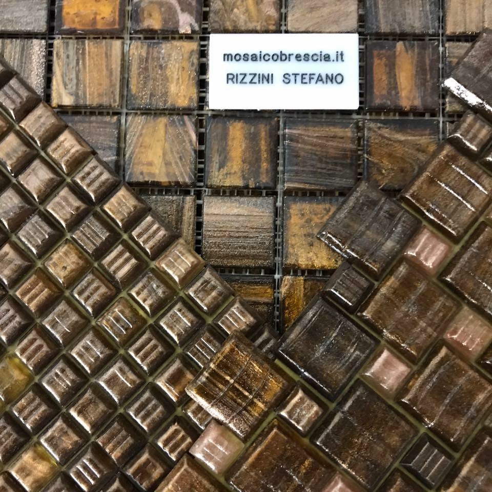 Artigiano con mascherina applica piastrelle blu e bianche su grande mosaico geometrico in interno.